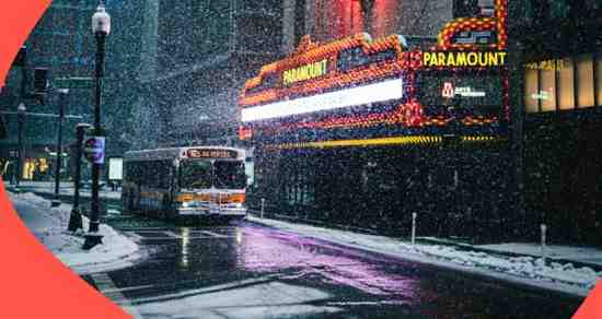 A bus is parked in front of a movie theater.