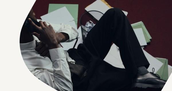 A man wearing a white shirt and black pants is laying on the floor.