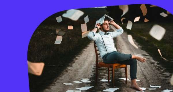 A man sitting on a chair with a stack of papers on his head.