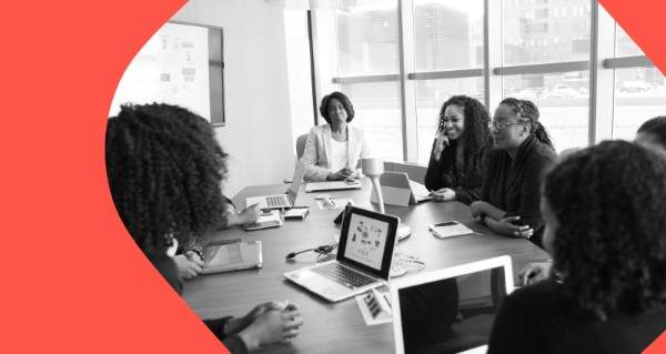 A group of people sitting around a table with laptops and a projector.