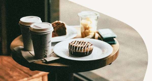 A table with a cup of coffee and a pastry on it.