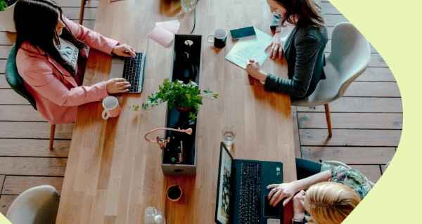 A woman is typing on a laptop at a table with other people.
