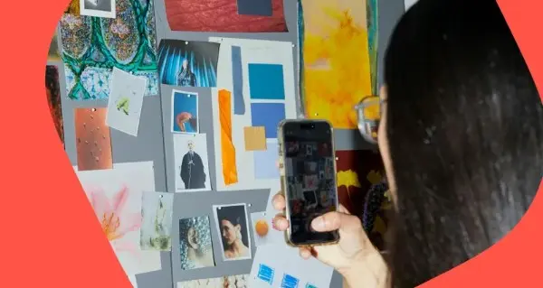 A woman is taking a picture of a cell phone with a picture of a man on it.