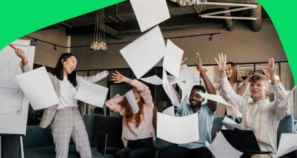 A group of people celebrating with paper flying in the air.