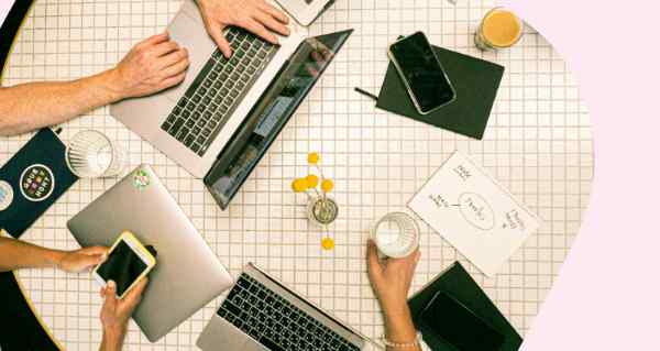 A laptop with a keyboard and a glass of orange juice on a table.