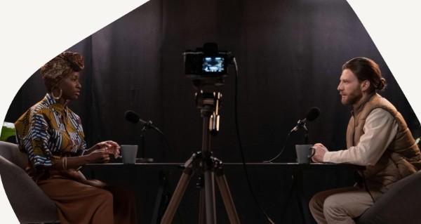 Two men sitting at a table with a camera in front of them.