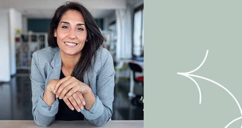 A woman wearing a gray jacket and smiling.