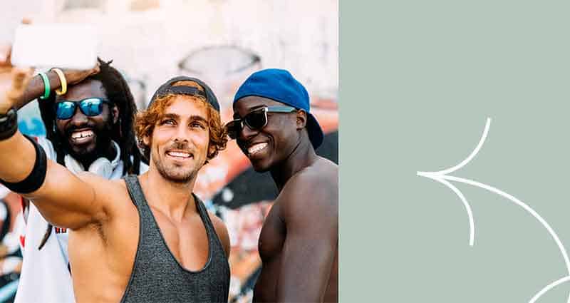 Three men wearing sunglasses and hats are smiling for the camera.