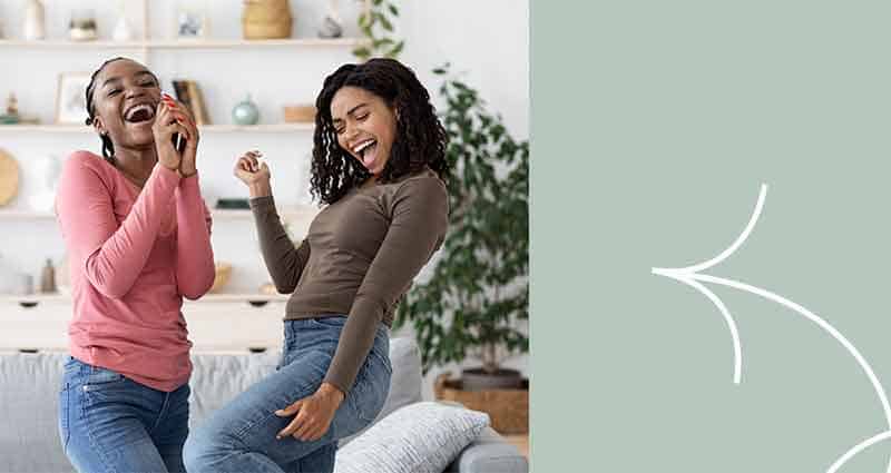 A woman in a brown shirt and blue jeans is laughing and dancing.