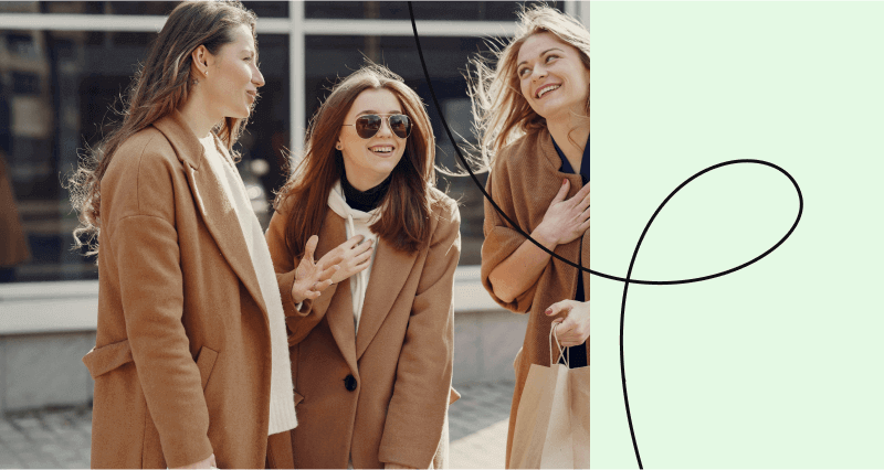 Three women wearing brown coats and sunglasses standing together.