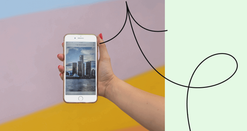 A person holding a phone with a picture of a city on the screen.