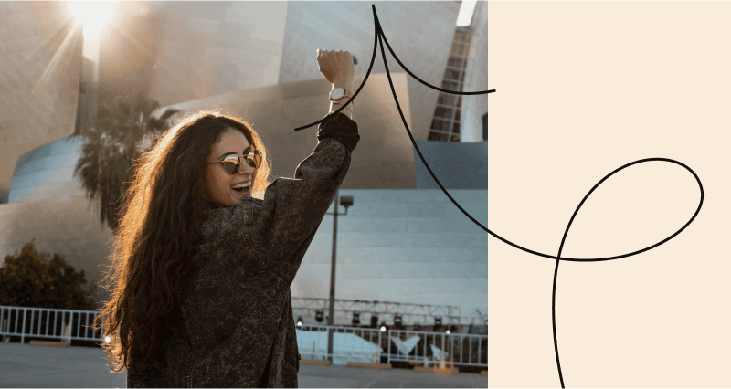 A woman wearing sunglasses and a black jacket is smiling.