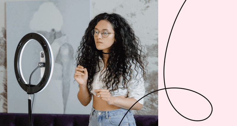 A woman with glasses and curly hair wearing a white shirt.