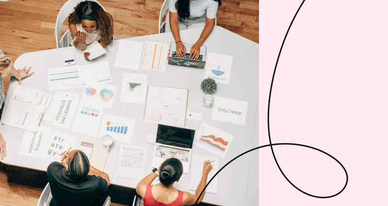 A woman sitting at a table with a laptop and papers.