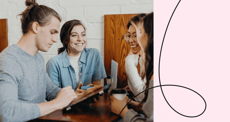 A group of people sitting around a table with a laptop and a coffee cup.