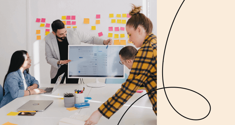 A woman in a yellow plaid shirt is pointing at a computer screen.