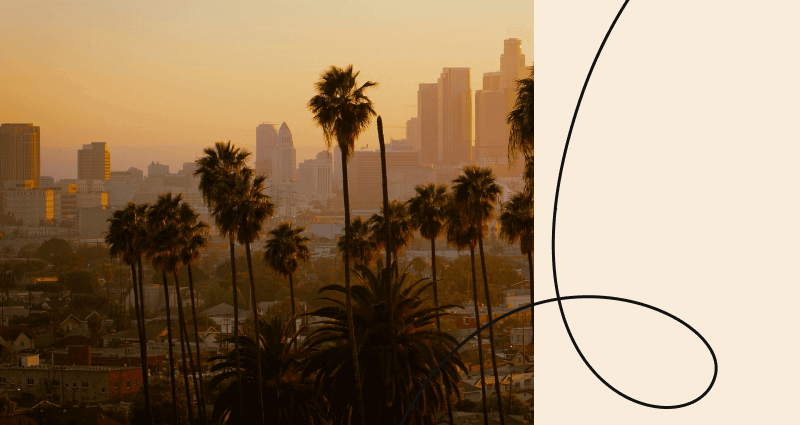 A cityscape with palm trees and a tall building in the background.