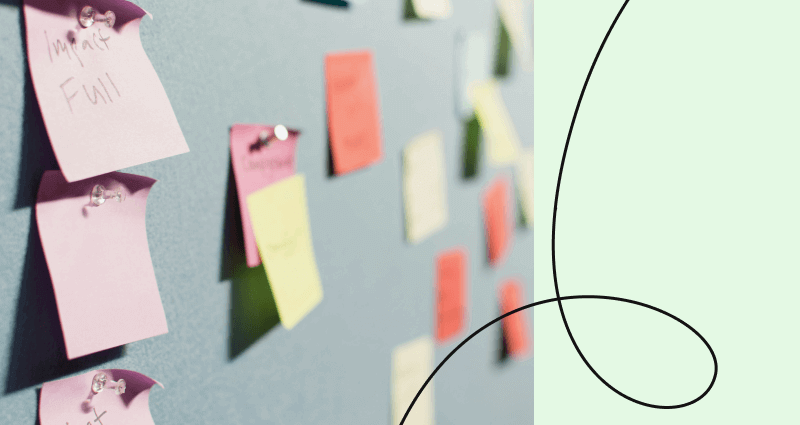 A bulletin board with yellow sticky notes and a green background.