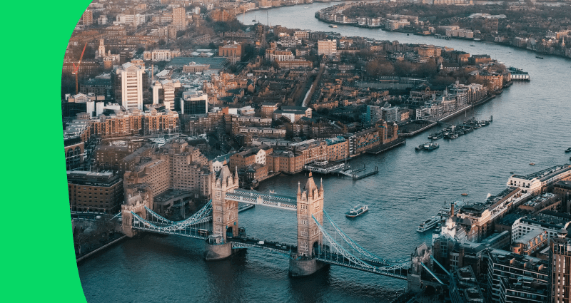 A black and white photo of a city with a bridge over a river.