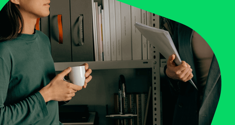 A man holding a white paper while a woman holds a cup of coffee.