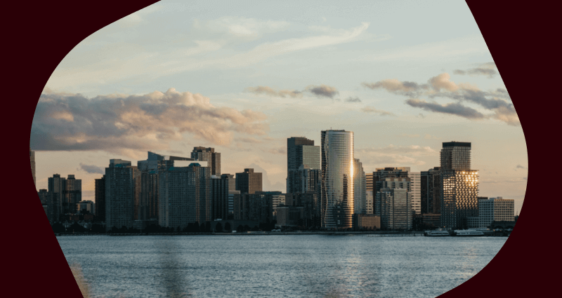A city skyline with a large building and a boat in the water.