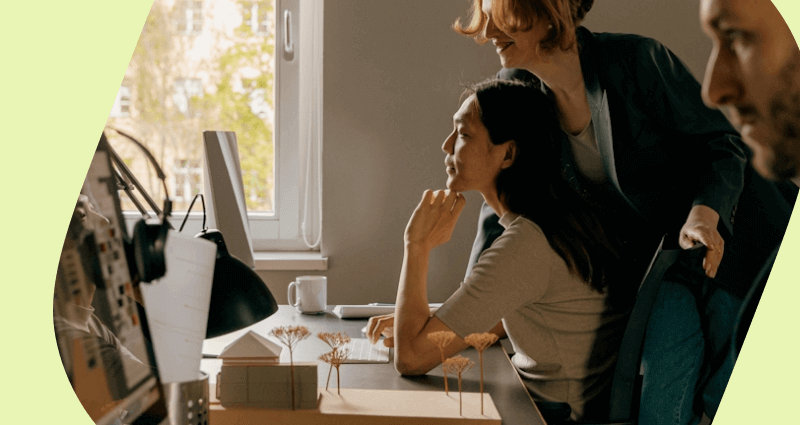 Two women sitting at a desk with a laptop and a cup of coffee.
