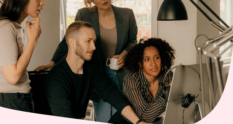 A man and woman are sitting in front of a laptop.