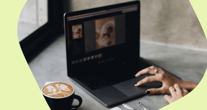 A laptop with a coffee cup and a pen on the desk.