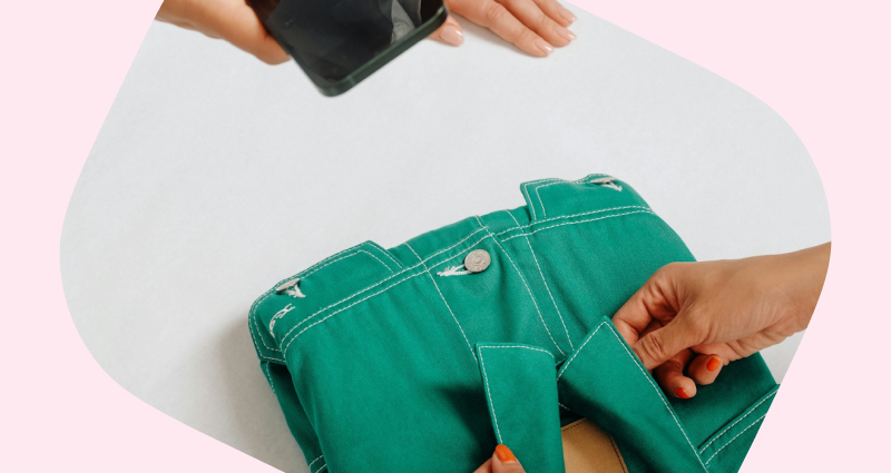 A person is holding a green jacket in their hand.