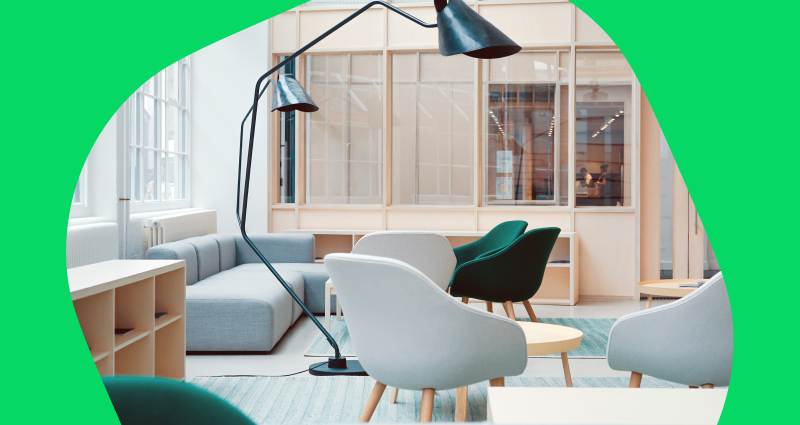 A large room with a green chair and a lamp.