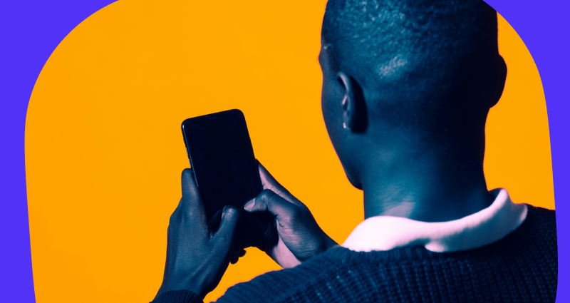 A man holding a cell phone with a yellow background.