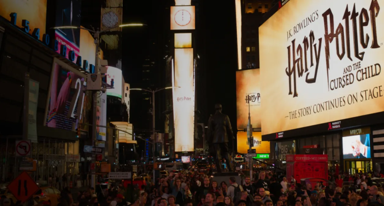Crowded Times Square at night featuring large digital billboards and outdoor advertising displays in New York City.
