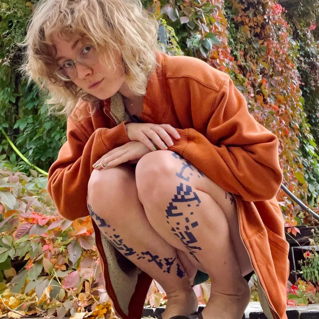 Lifestyle portrait of a content creator posing outdoors in an oversized orange jacket against an autumn backdrop. The image showcases an authentic, personality-driven aesthetic often used in influencer marketing, lifestyle branding, and user-generated content (UGC) campaigns to build audience trust and engagement.