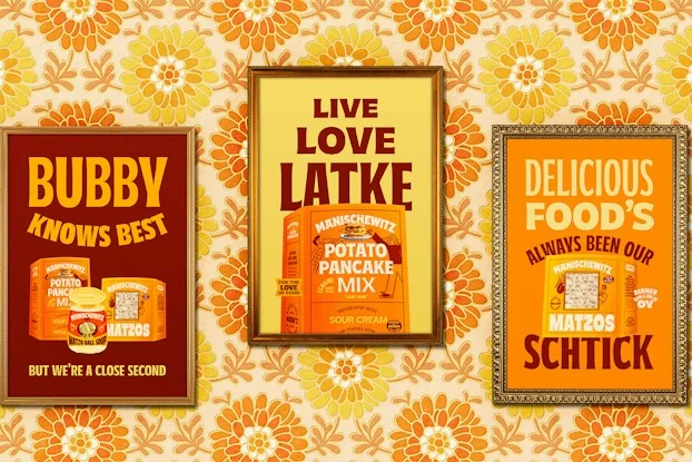 Three framed posters show Manischewitz food products with slogans like 'Bubby knows best' and 'Delicious food's always been our schtick' against patterned wallpaper.