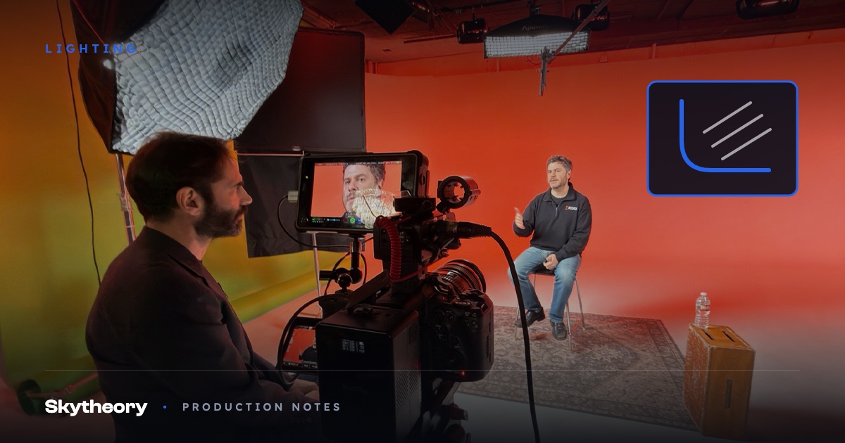 Interview subject seated on a cyc wall lit deep red-orange with a DP at camera in the foreground, with a cove curve and raking light graphic