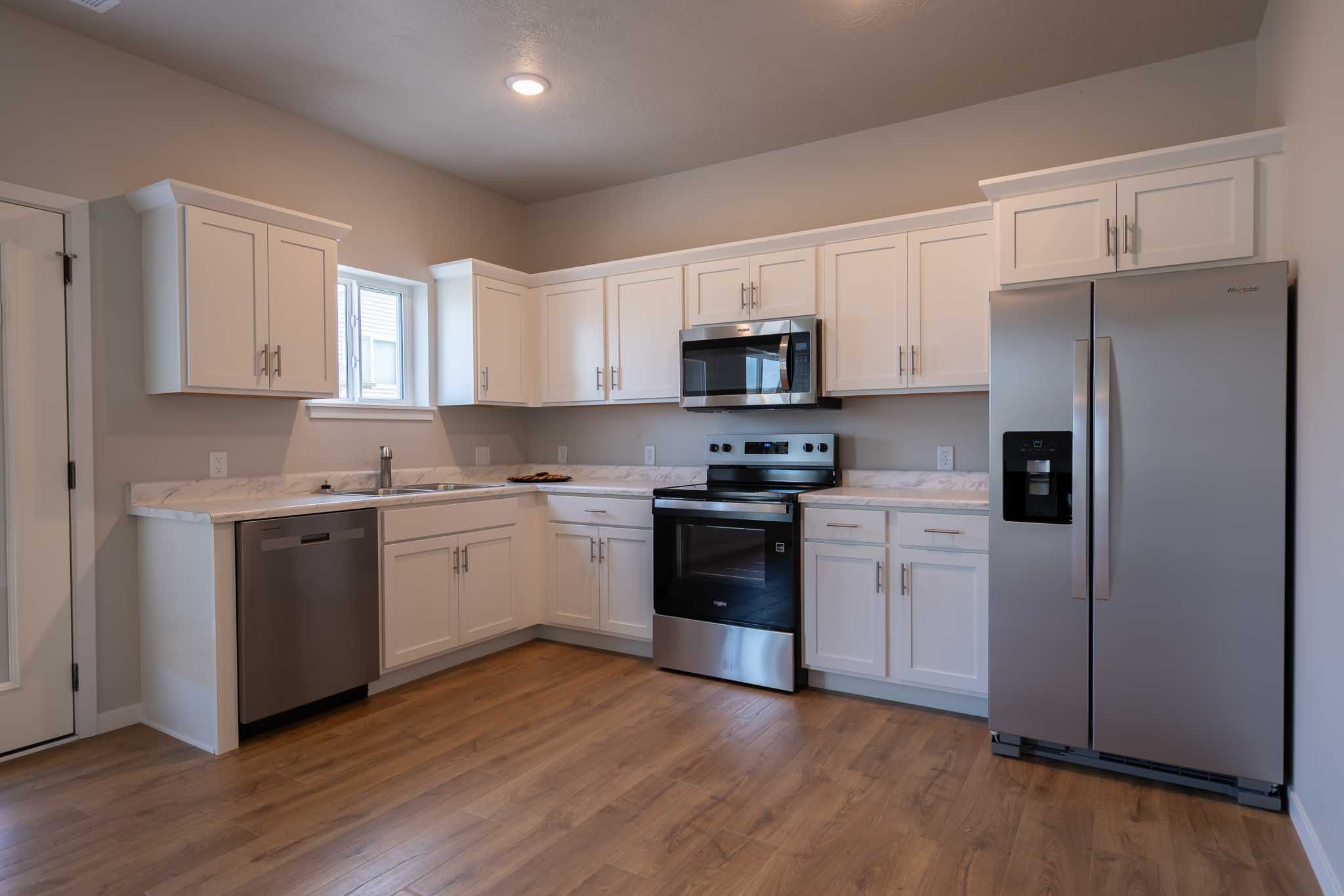 Apartment kitchen with white cabinets and stainless steel appliances.