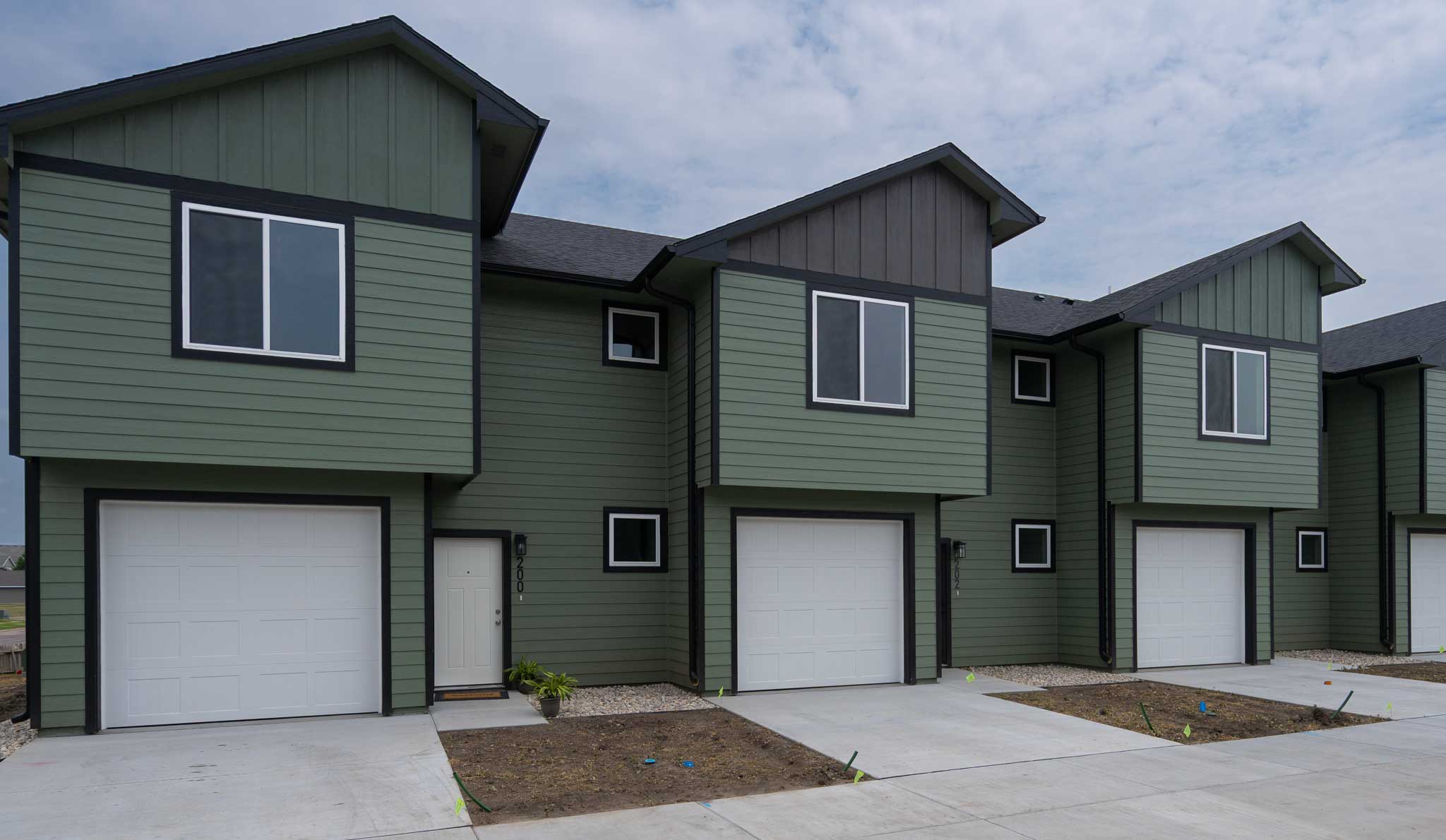 Fourplex painted green with black trim.