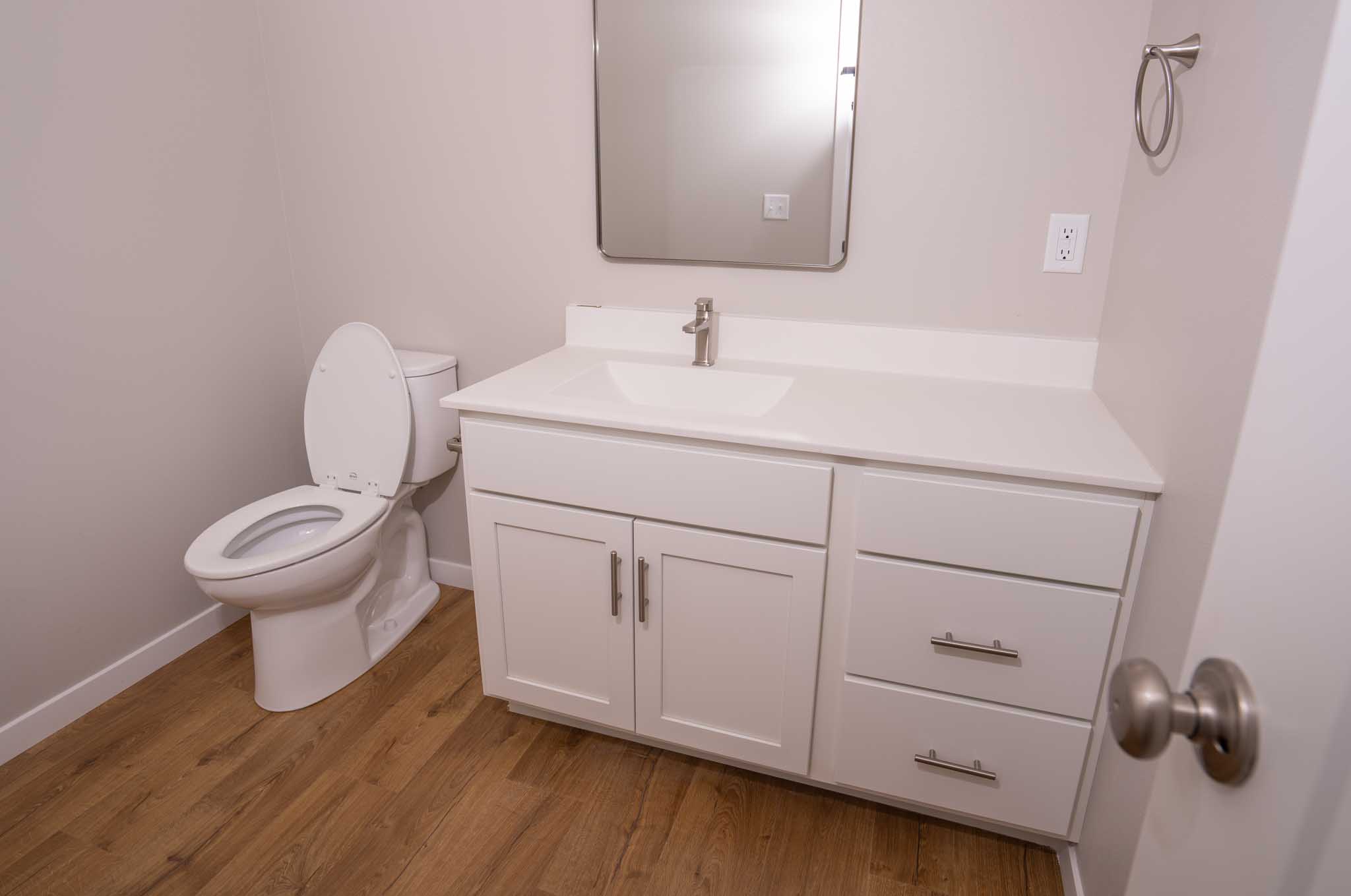 A bathroom with white toilet and white cabinets.