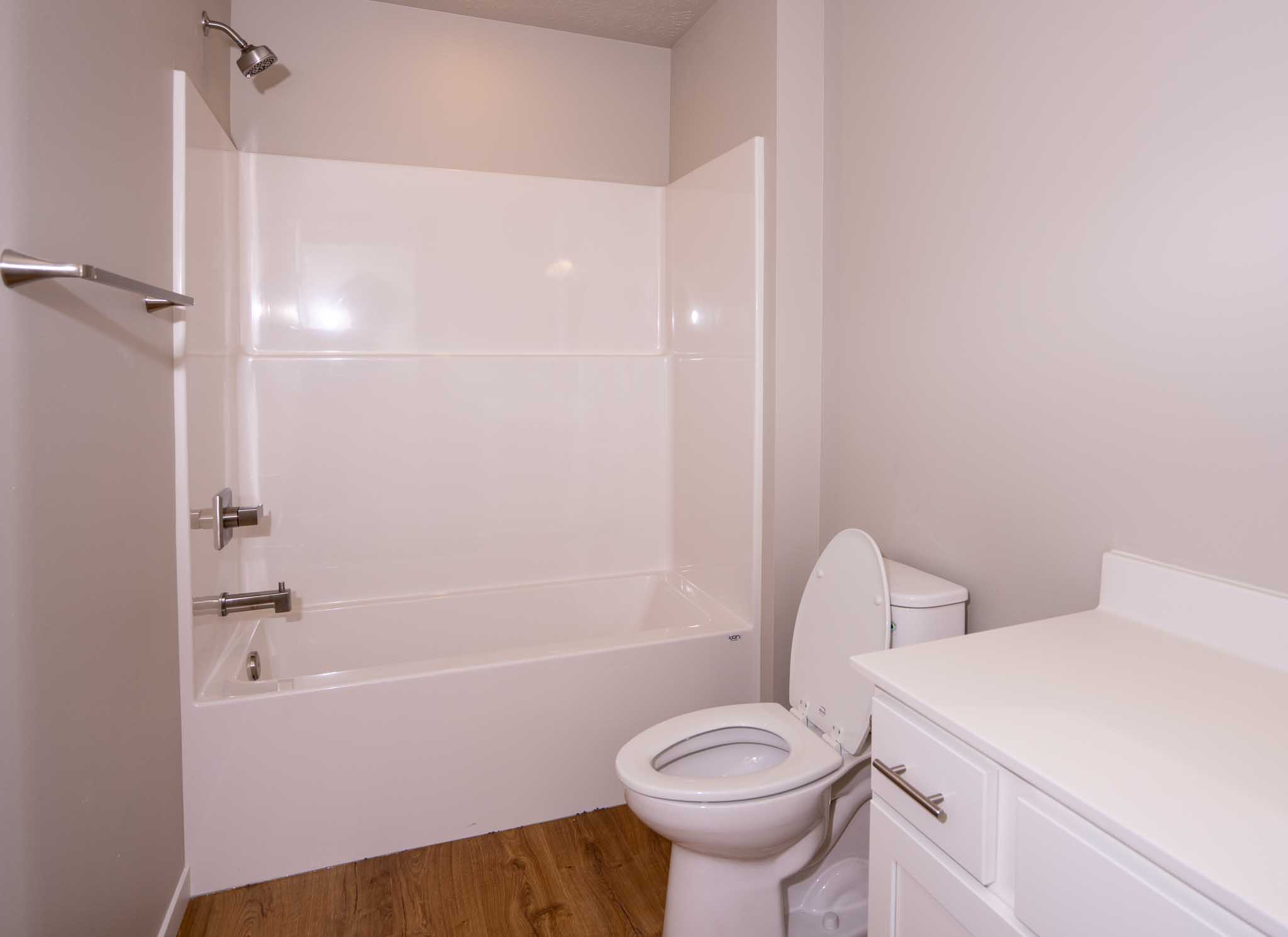 A bathroom with tub/shower combo and white vanity.