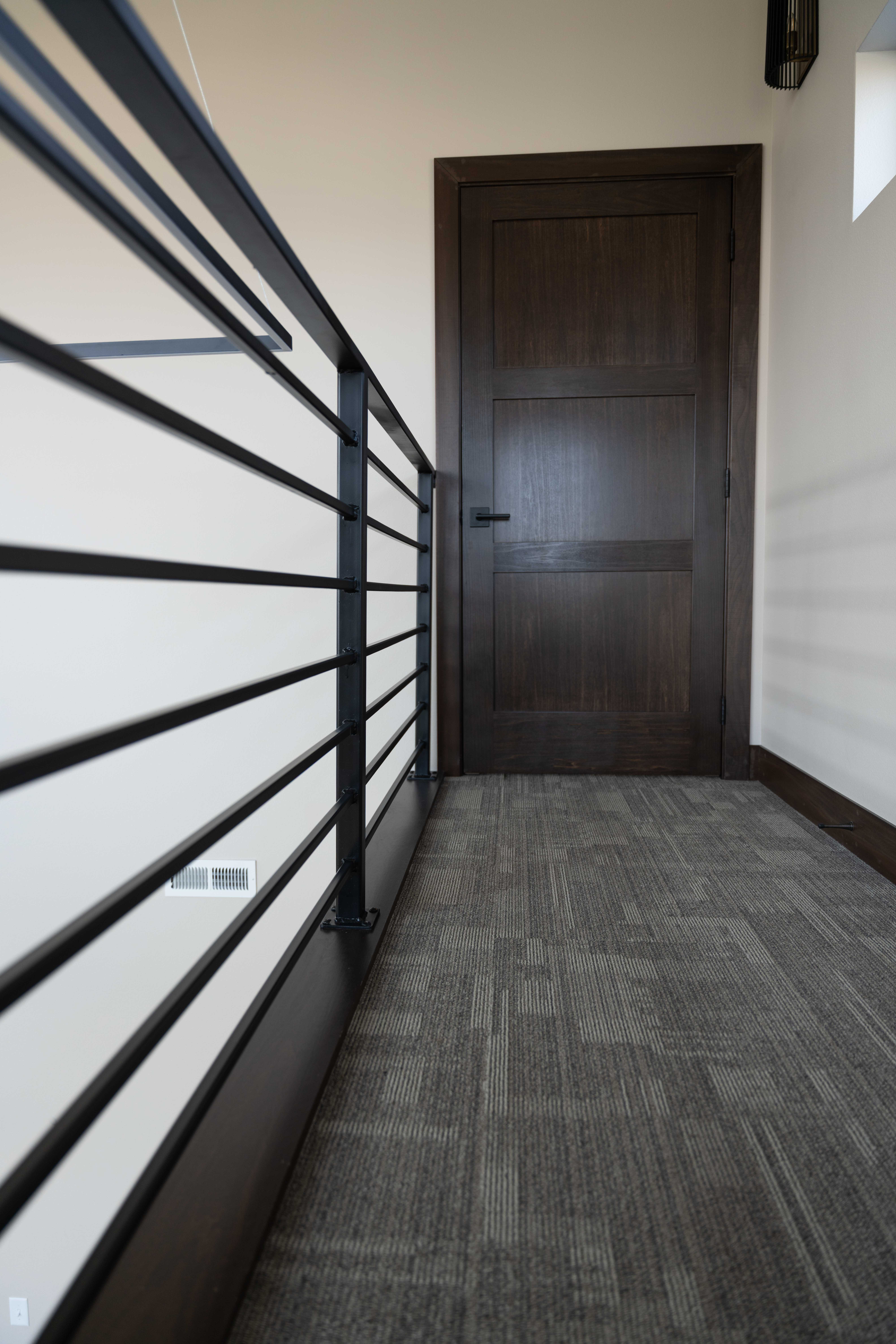 Black metal railing with a dark stained door.
