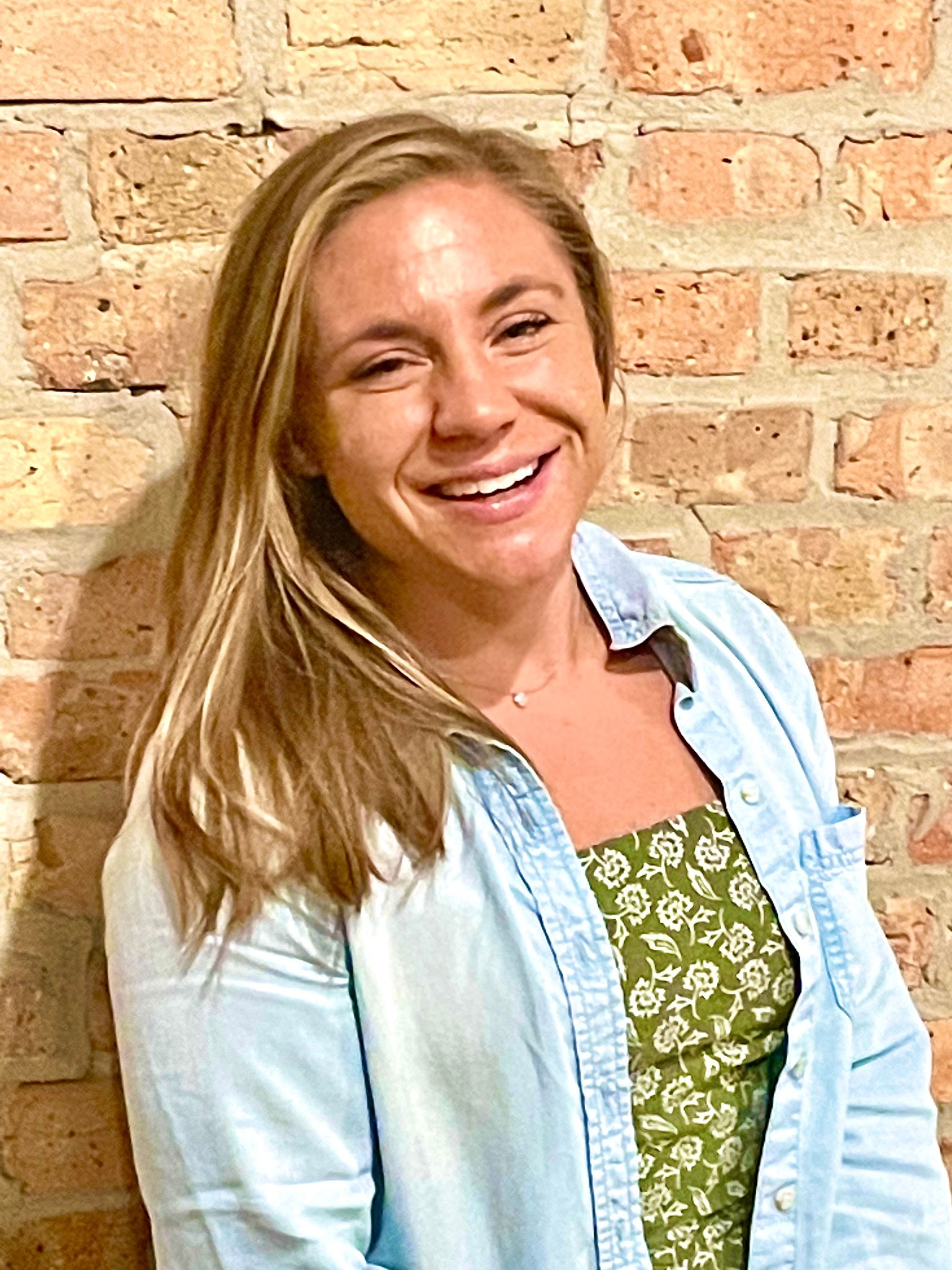 Dana Bonnecarre smiling in a denim shirt against a brick wall, telehealth-only therapist at Grow Wellness Group
