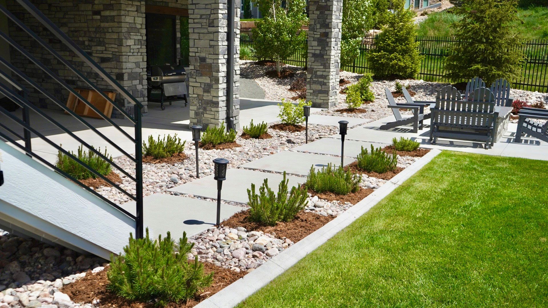 Well-maintained outdoor area with clean walkways, greenery, decorative stone, and seating by Belmire.