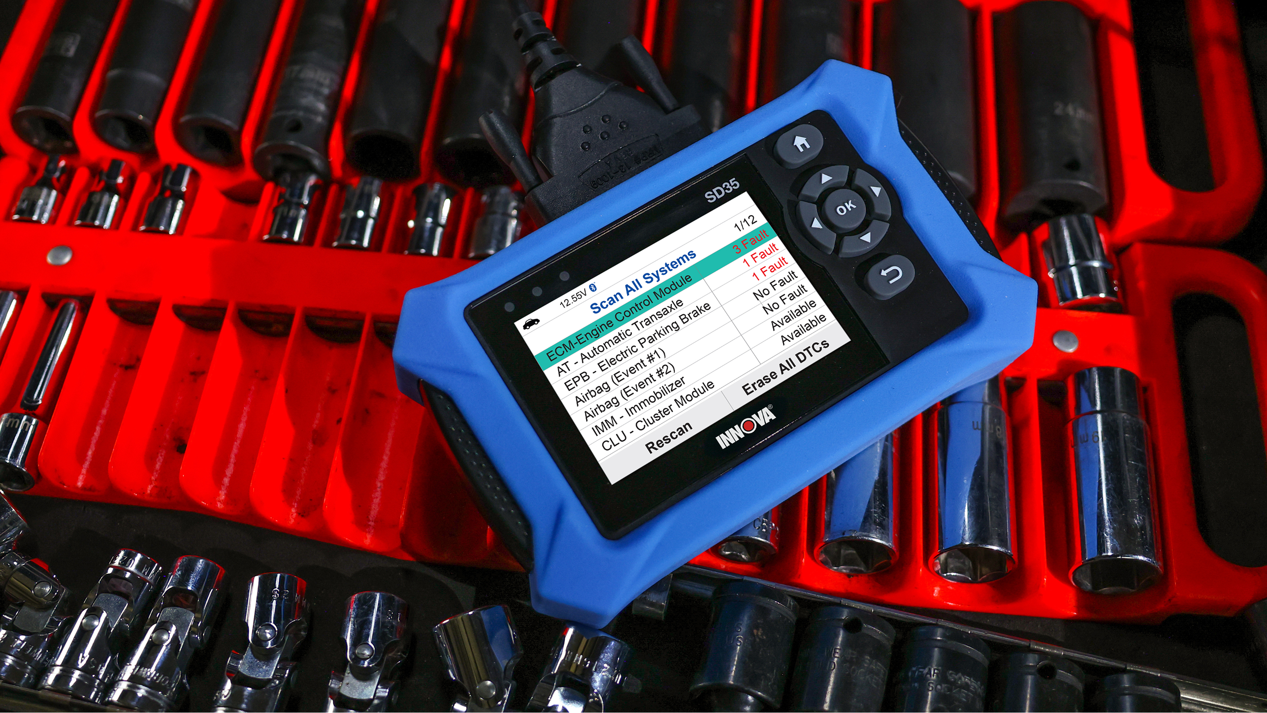 INNOVA SD35 automotive diagnostic scanner displaying a system scan with some faults detected, placed on a red tool tray with various sockets and automotive tools.