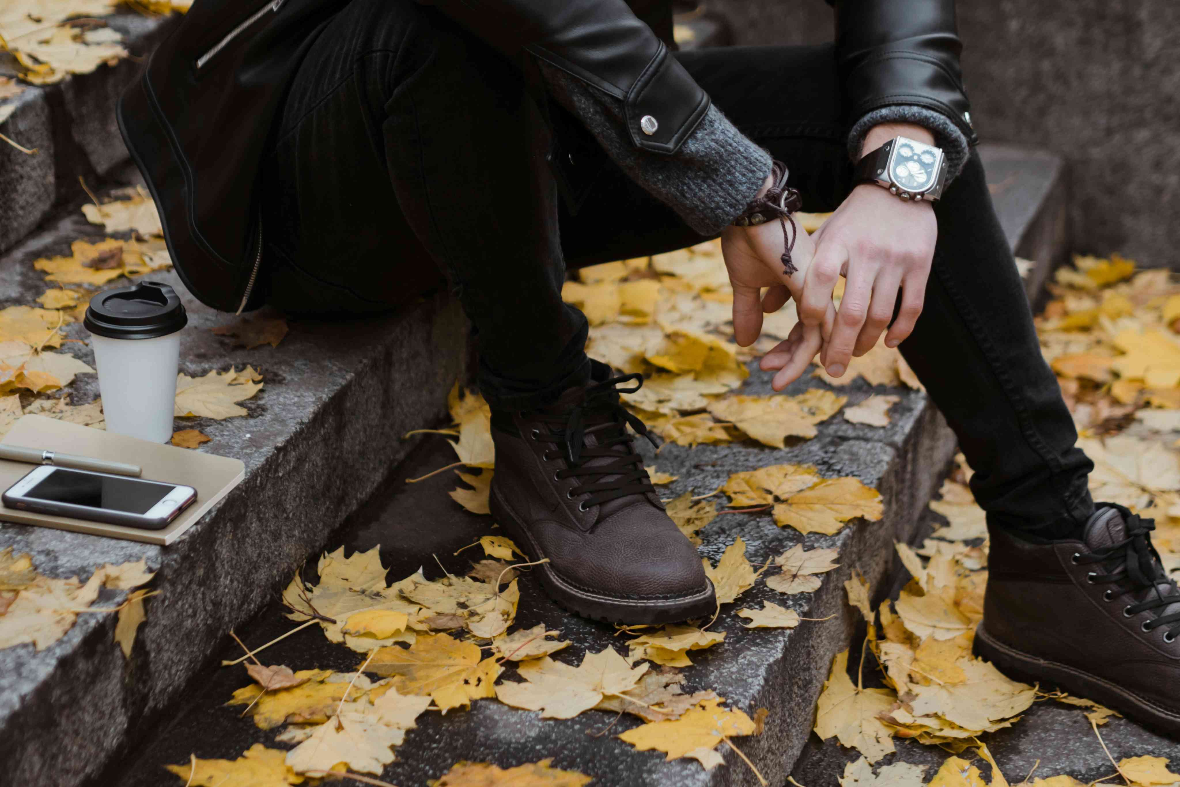Person in Black Leather Jacket and Black Jeans Sitting on Concrete Stairs