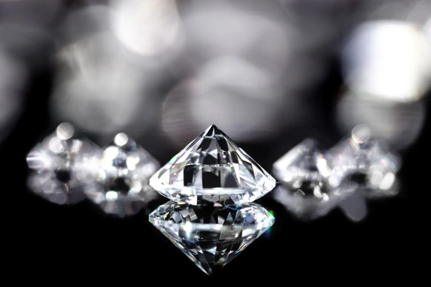 Brilliant-cut diamonds against a black background with reflections
