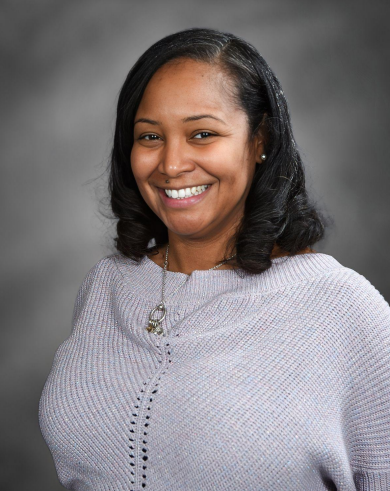 Ms. Shanieka Muniz smiling in a Black Excellence sweatshirt