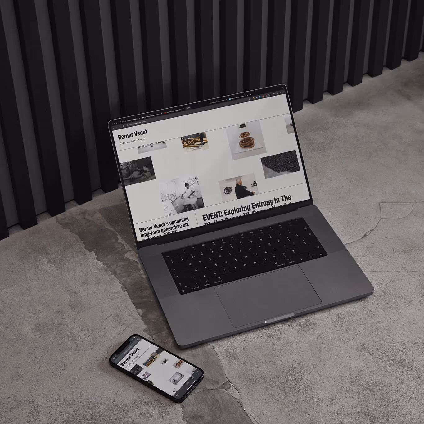 Laptop and smartphone on concrete floor displaying Bernar Venet digital art studio website.