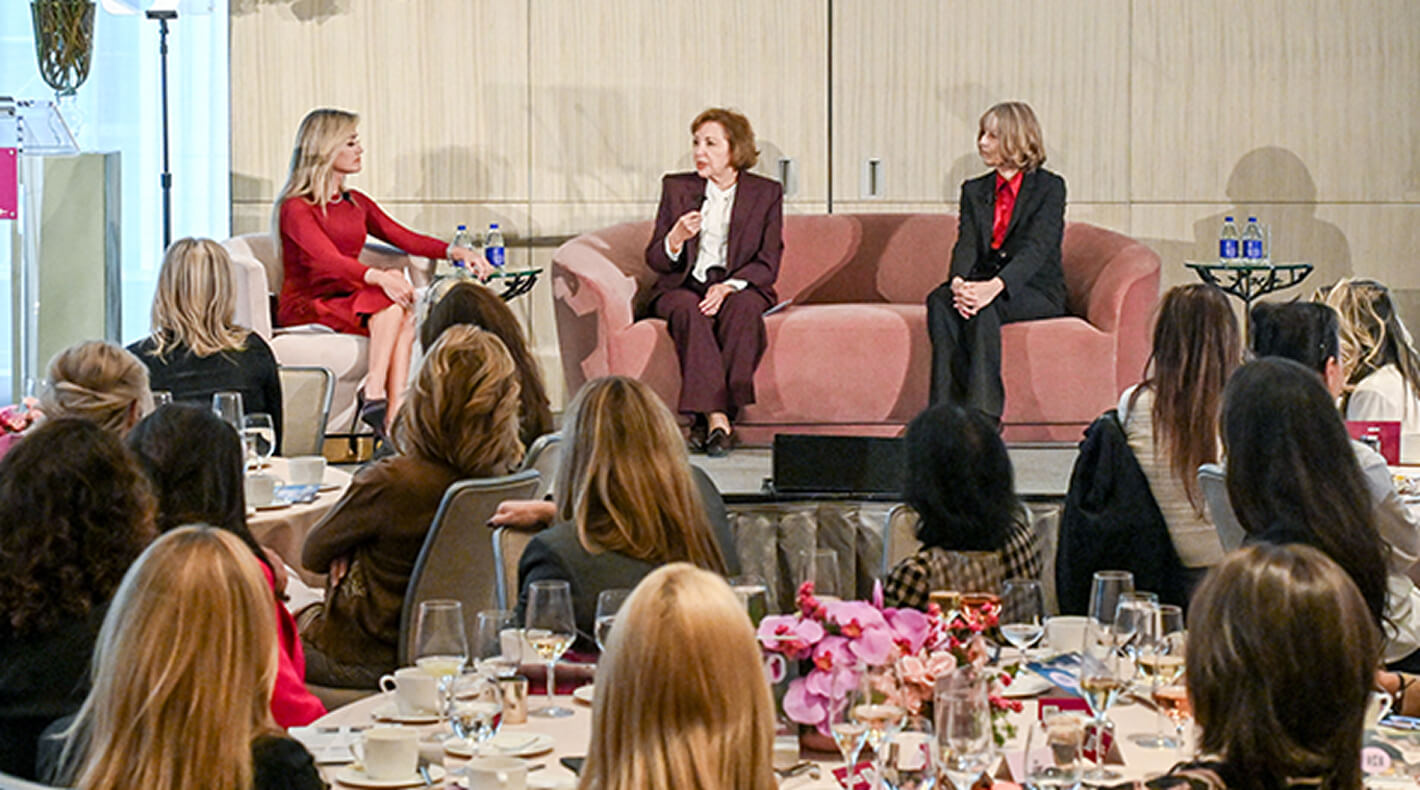 Three women in conversation, sitting on a couch on stage