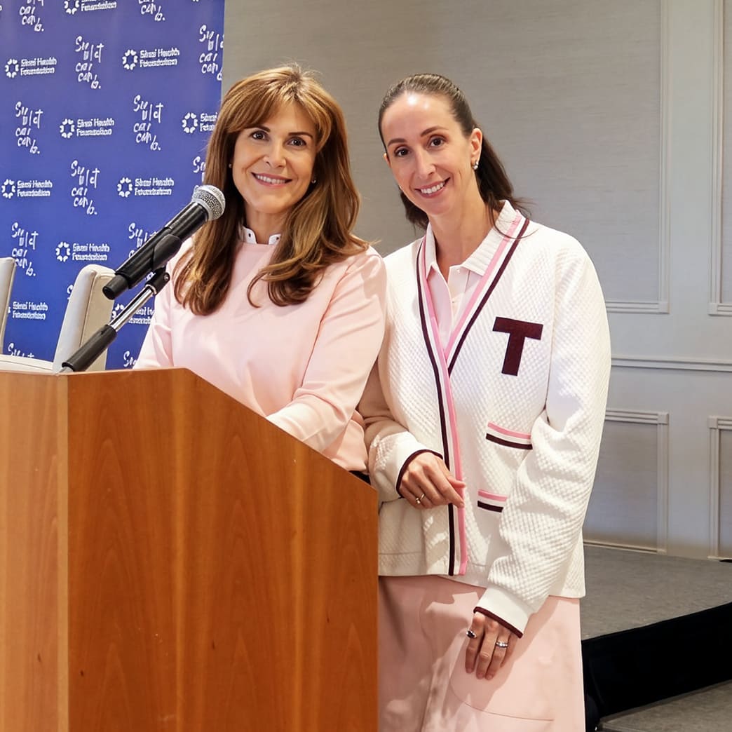 Two women stand smiling at a podium