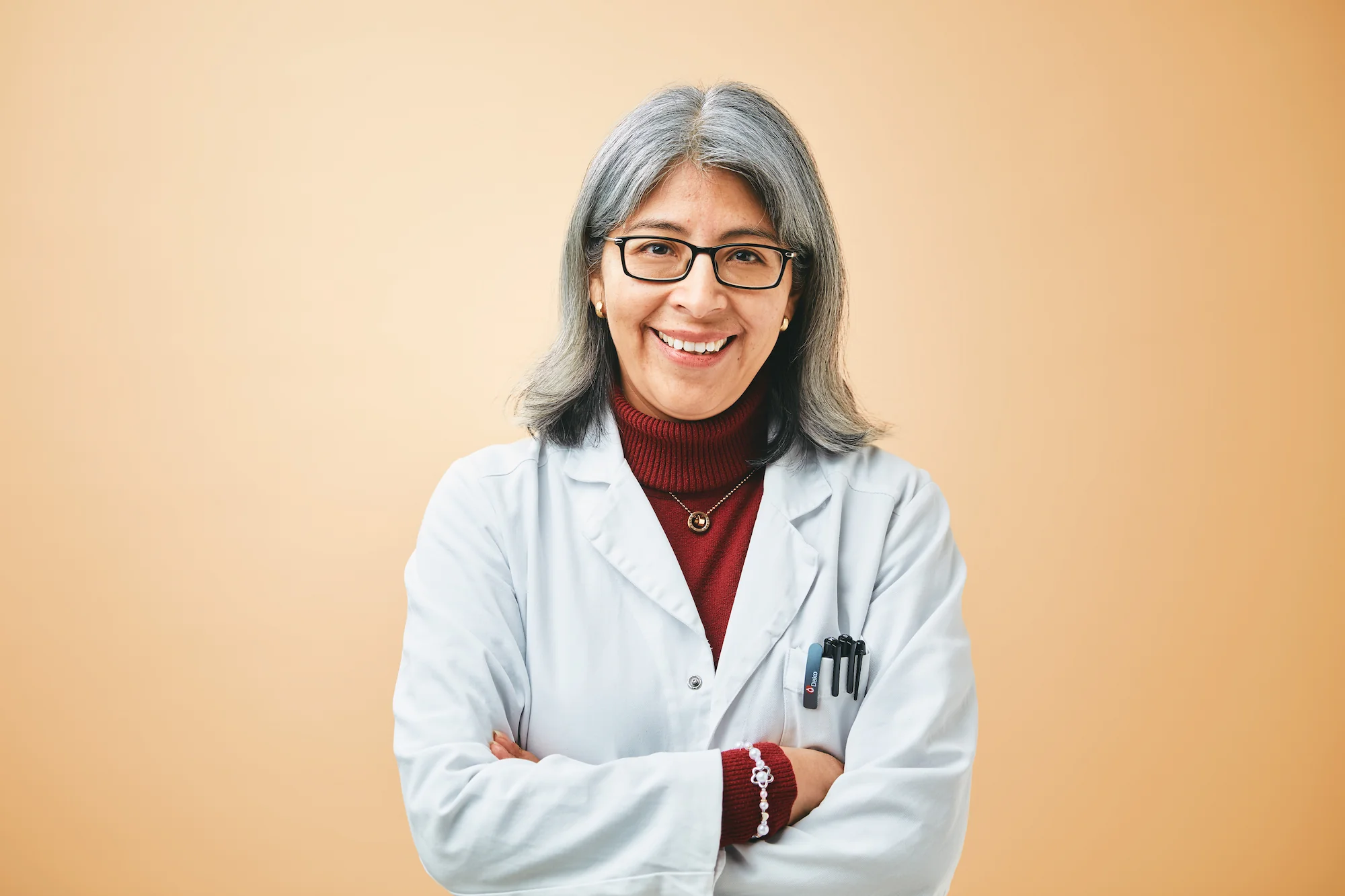 Portrait of Nélida Leiva Eriksson smiling in a lab coat with arms crossed